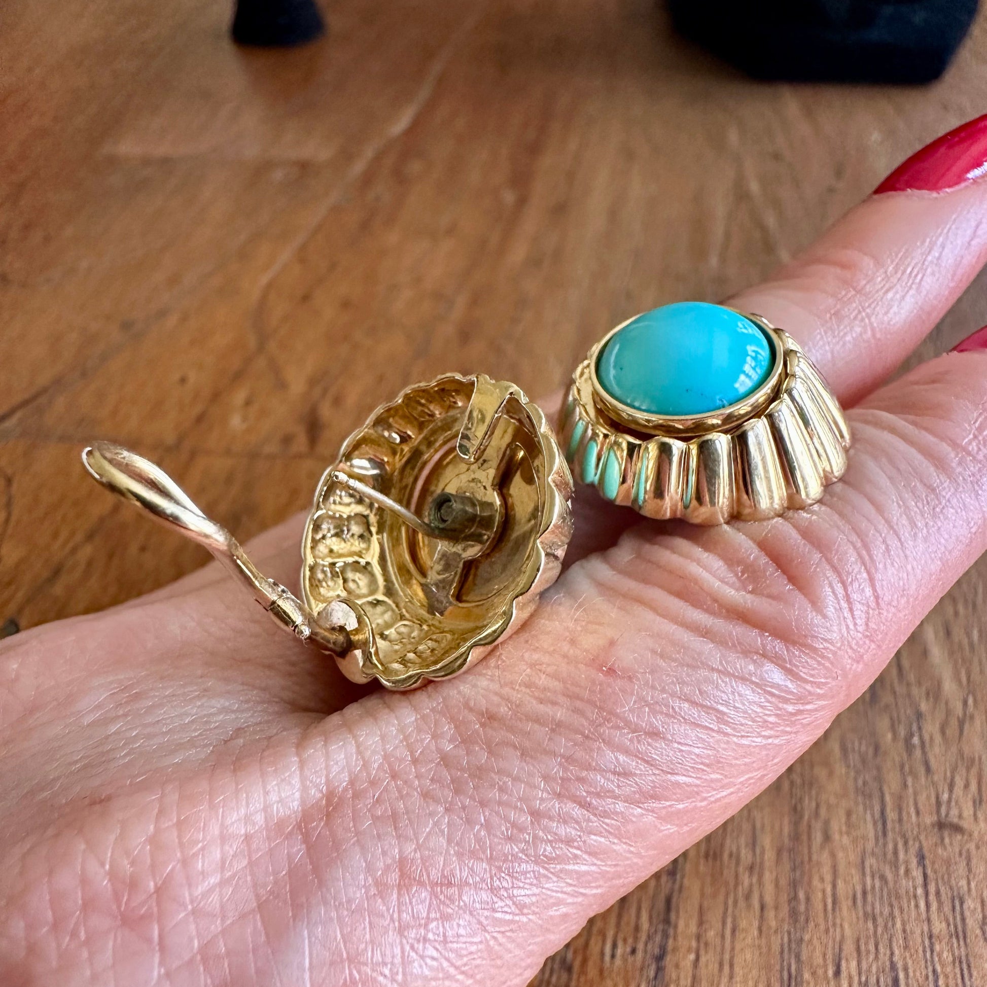A pair of 14k gold clip-on earrings with oval turquoise-blue stones.