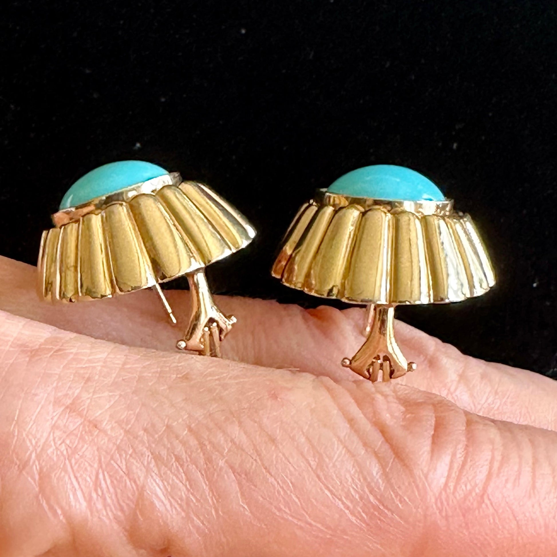 A pair of gold dome-shaped earrings with turquoise blue top stones