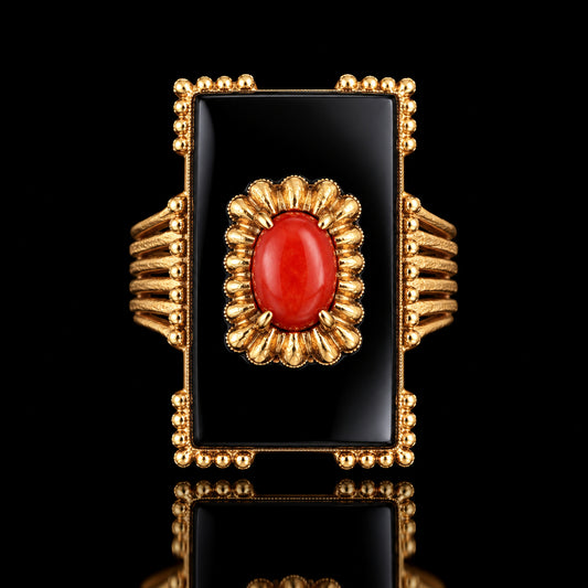 A rectangular black onyx ring with 14k gold scalloped border and a central coral cabochon